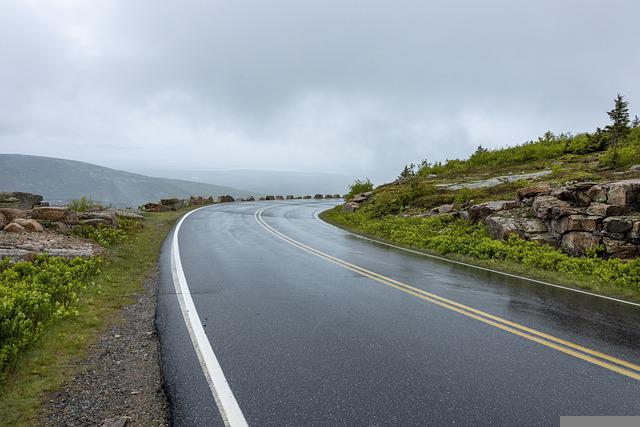 A wet road with mountains in the background on a cloudy day in Acadia NP