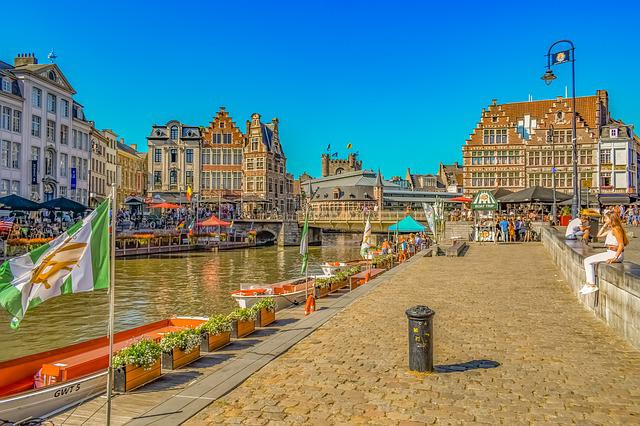 A group of people are sitting on a pier next to a river in Amsterdam