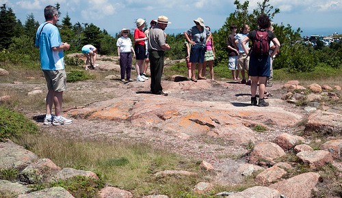 A group of people listening to a ranger talk on top of a rocky hill in Acadia NP