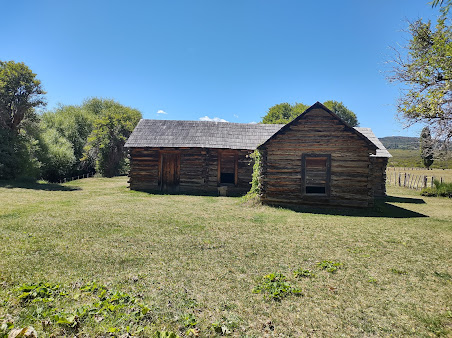 There are two log cabins where Butch Cassidy lived in the middle of a grassy field.