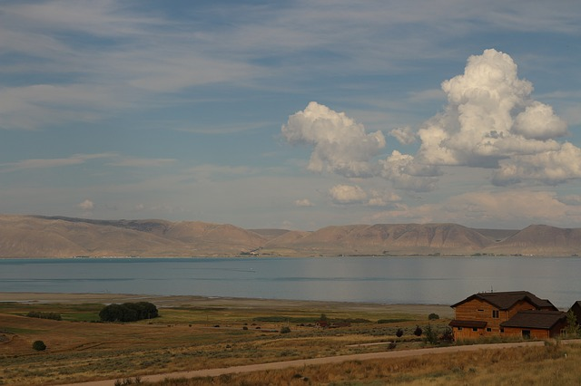 There is a house in the middle of a field next to a lake.