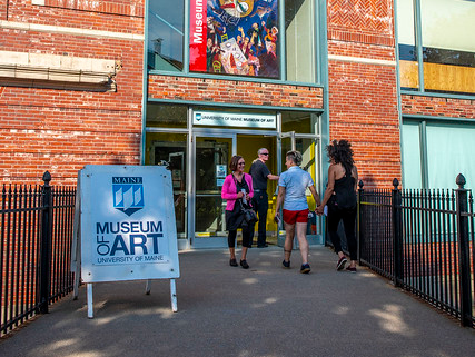 A group of people are standing outside the Bangor museum of art.