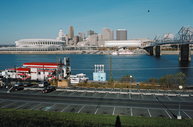 The Cincinnati skyline with a bridge over a body of water and a parking lot in the foreground.