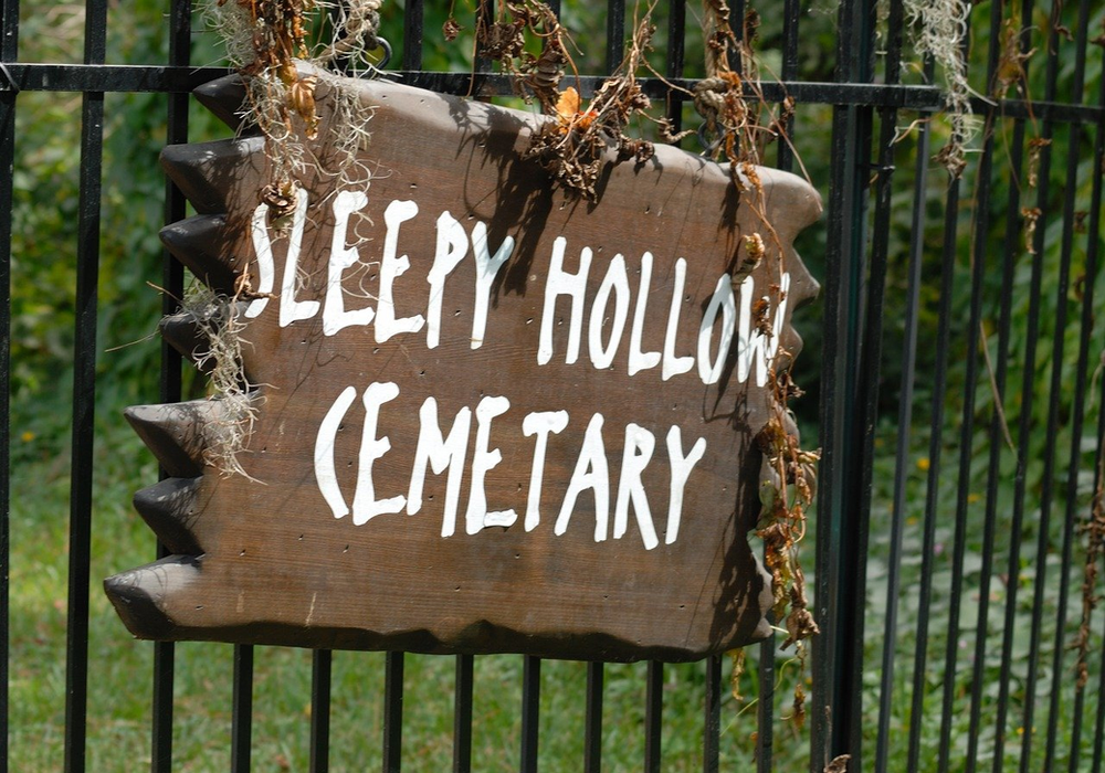 A sign on a fence that says sleepy hollow cemetery