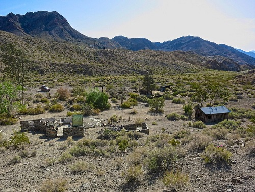 A small house in the middle of  Death Valley National Park with mountains in the background.