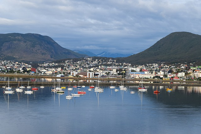 Boats are docked in a harbor with mountains in the background