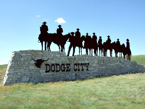 A sign that says dodge city with cowboys on horses