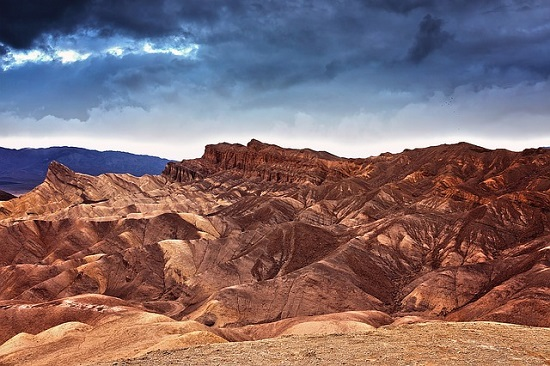 A desert landscape with mountains in the background and a cloudy sky  in Death Valley National Park