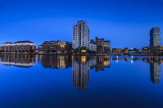 The dublin skyline is reflected in a body of water at night.