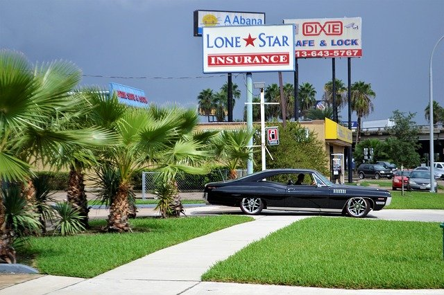 A black car is parked in front of a lone star insurance sign