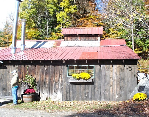 A man standing in front of a wooden building with a red roof in Montpelier