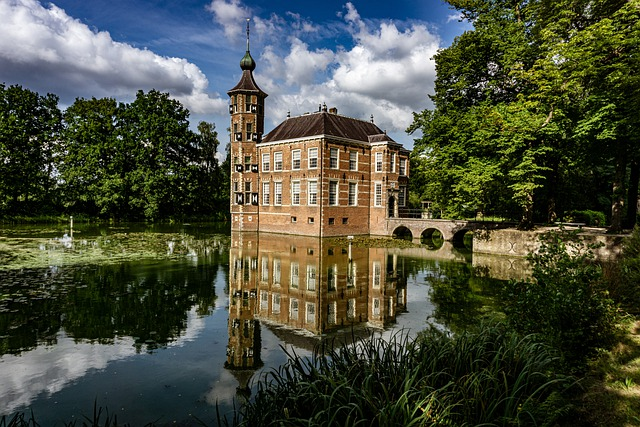 A castle is reflected in the water of a lake surrounded by trees.