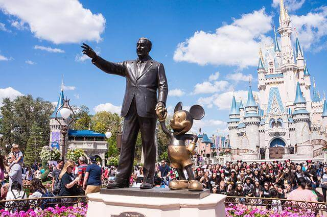 A statue of Walt Disney and Mickey Mouse in front of the Cinderella Castle.