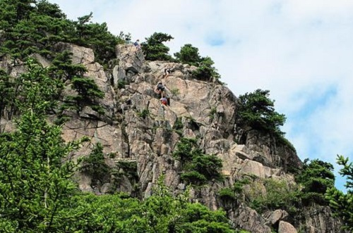 A group of people are climbing up the side of a mountain in Acadia NP