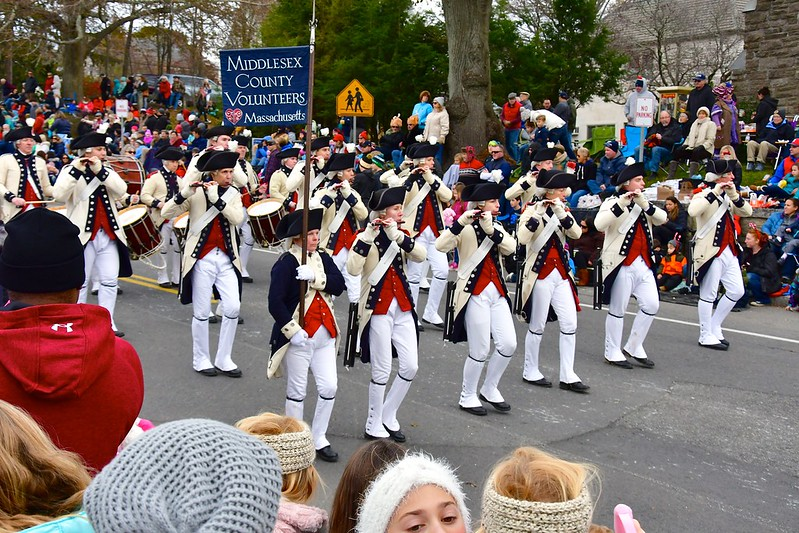 A marching band is marching down a street in front of a crowd in Plymouth