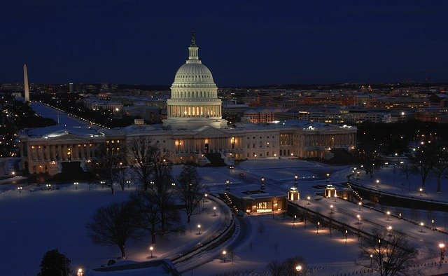 The US capitol building is lit up at night in the snow