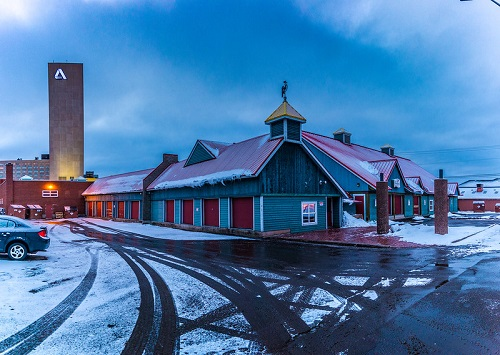 A car is parked in front of a building with a tower in the background in Moncton