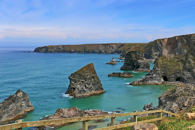 A wooden fence surrounds a cliff overlooking a body of water in Cornwall