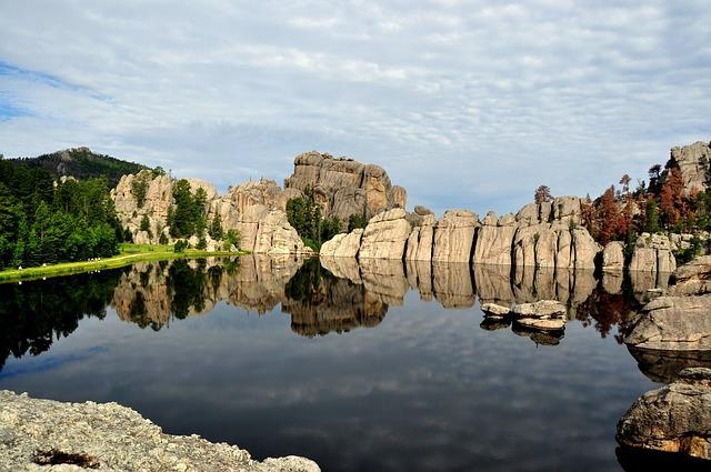 A lake surrounded by rocks and trees with mountains in the background in the black hills