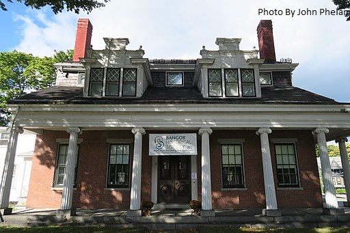 A large brick house with columns and a chimney in Bangor