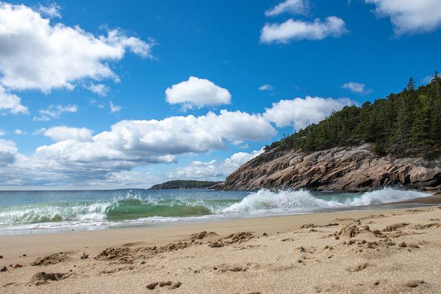 A beach with waves crashing against the shore on a sunny day in Acadia NP