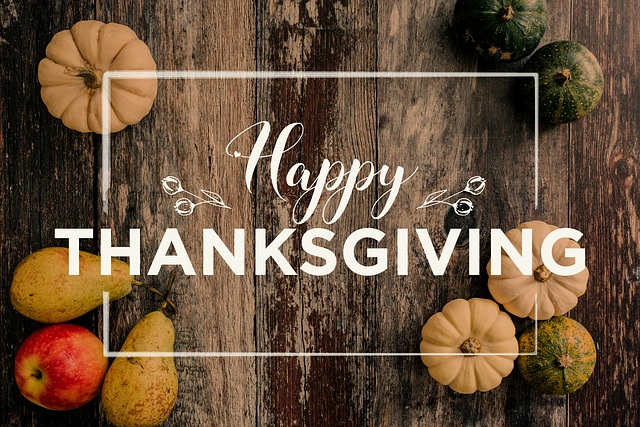 A wooden table topped with pumpkins , apples , pears and the words `` happy thanksgiving ''.