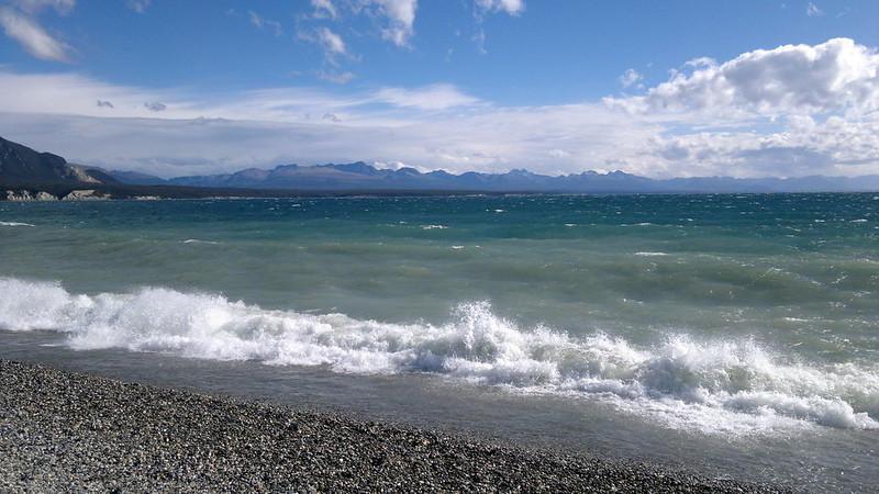 Waves crashing on a rocky beach with mountains in the background