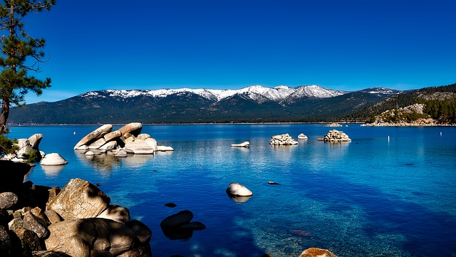 Lake Tahoe with mountains in the background and rocks in the foreground.