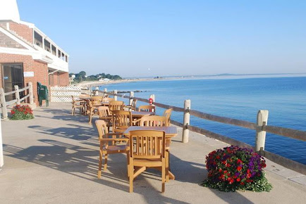 A patio with tables and chairs overlooking the ocean in Plymouth