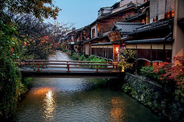 There is a bridge over a river in the middle of Kyoto