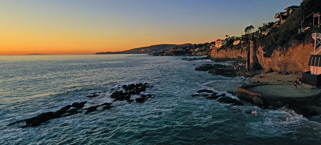 An aerial view of a cliff overlooking the pacific ocean at sunset.