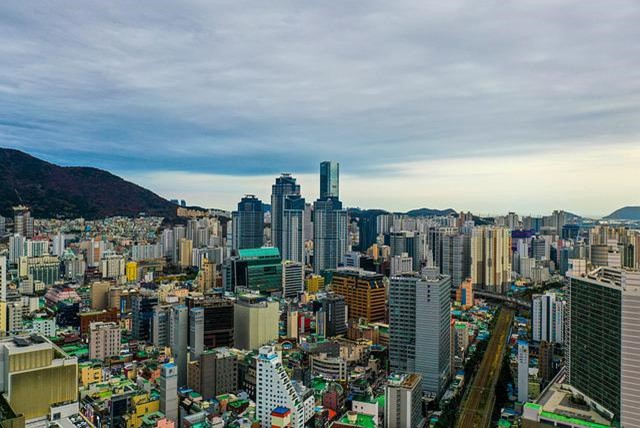 An aerial view of Busan with mountains in the background.