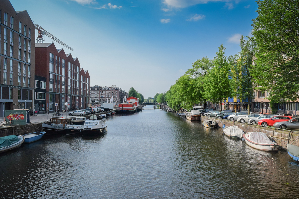 A river with boats docked on the side of it in Amsterdam.