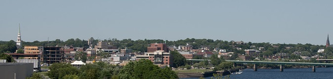 A picture of a new england city with a river in the foreground