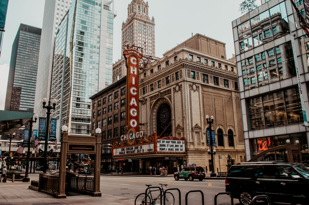 A city street in Chicago with a famous building in the middle of it.