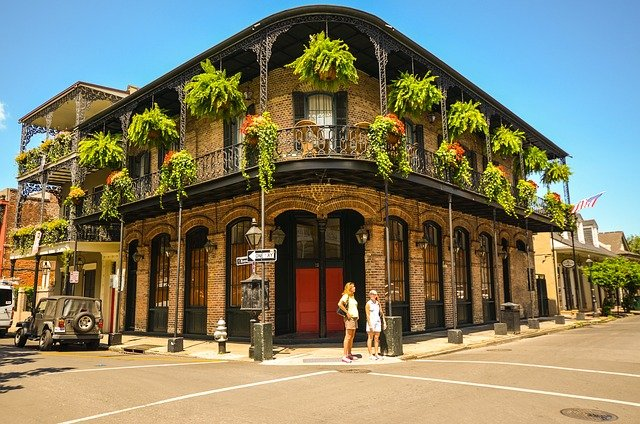 A couple of people are standing in front of a building with balconies in New Orleans