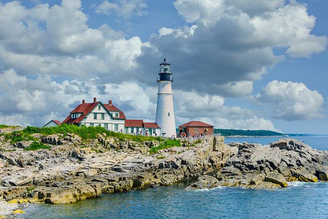 A lighthouse is sitting on top of a rocky cliff overlooking the ocean in Portland