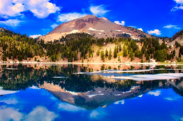 A mountain in Lassen Volcanic is reflected in a lake with trees in the background.