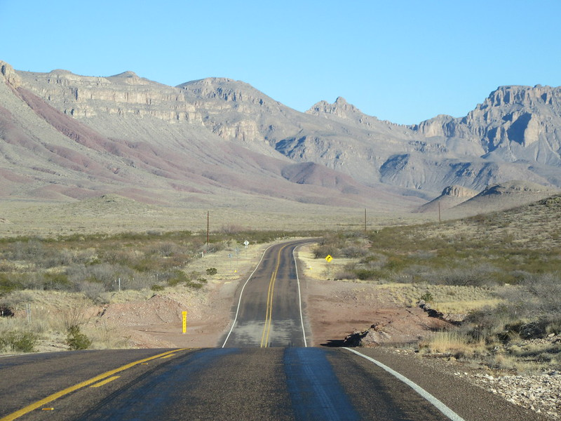 A road in the desert with mountains in the background in guadalupe mountains np