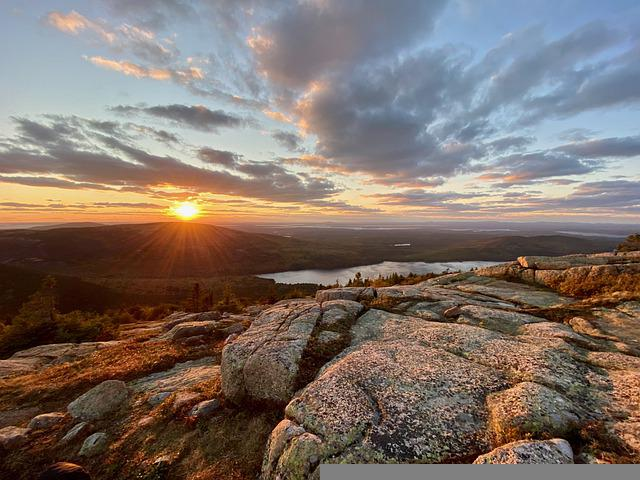 The sun is setting over a lake surrounded by rocks in Acadia NP