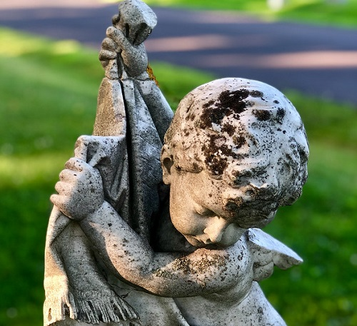 A statue of a cherub holding a flag in his hands in a Bangor cemetary