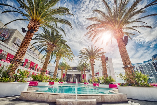 A swimming pool surrounded by palm trees in front of a building in Las Vegas.