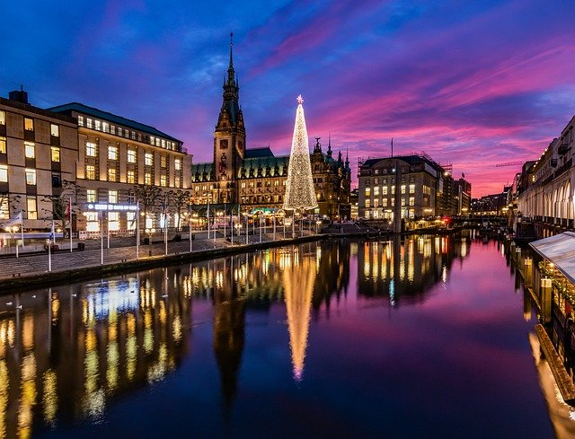 There is a Christmas tree in the middle of the city next to a river in Hamburg