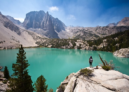 A person standing on a rock overlooking a lake with mountains in the background  in Death Valley National Park