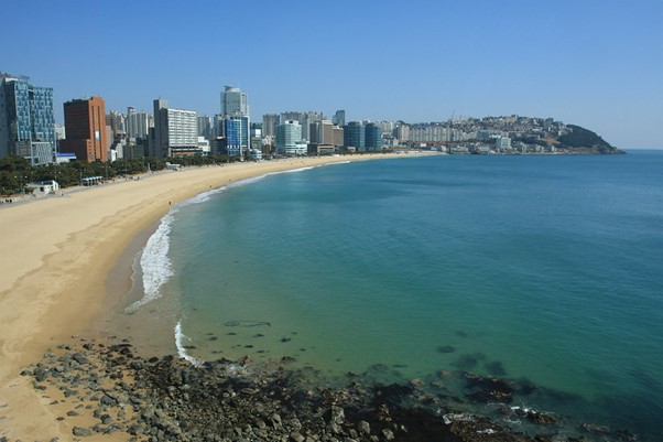 An aerial view of a beach in Busan with a city in the background