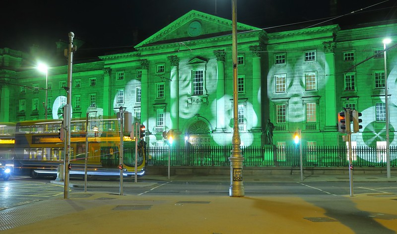 A large building is lit up with green lights at night in dublin