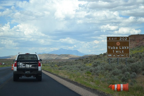 A car is driving down a highway next to a sign that says exit 202.