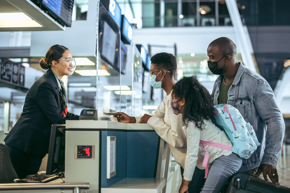 A family wearing face masks is checking in at an airport.