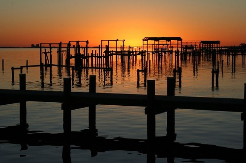 A sunset over a body of water with a dock in the foreground