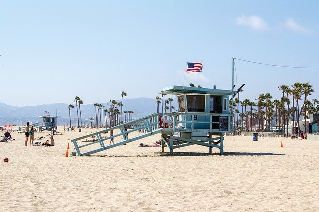 A lifeguard tower on Santa Monica beach with palm trees in the background.